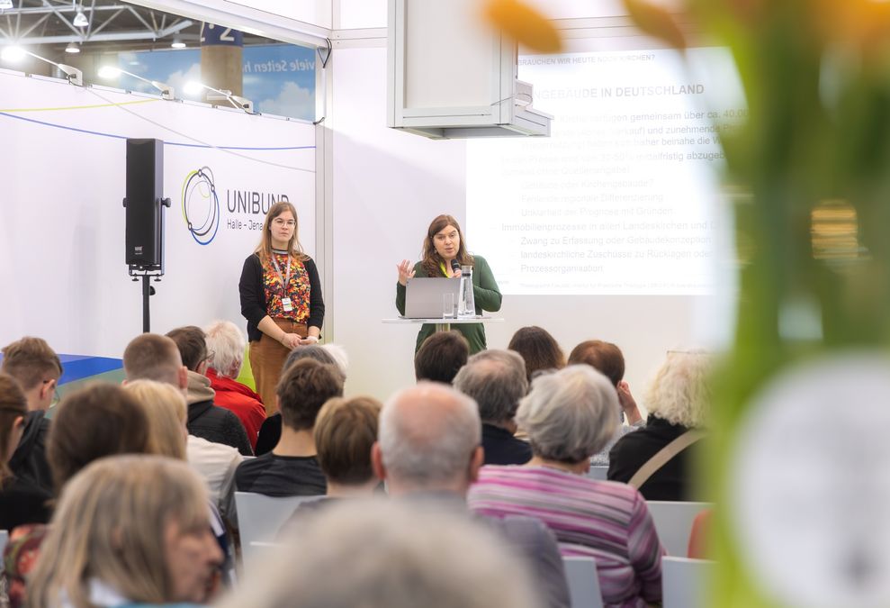 zur Vergrößerungsansicht des Bildes: Zwei Wissenschaftlerinnen halten eine Präsentation am Messestand