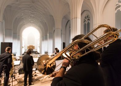 Ein Trompeter steht mit dem Rücken zur Kamera. Sein Instrument steht im Fokus des Bildes.