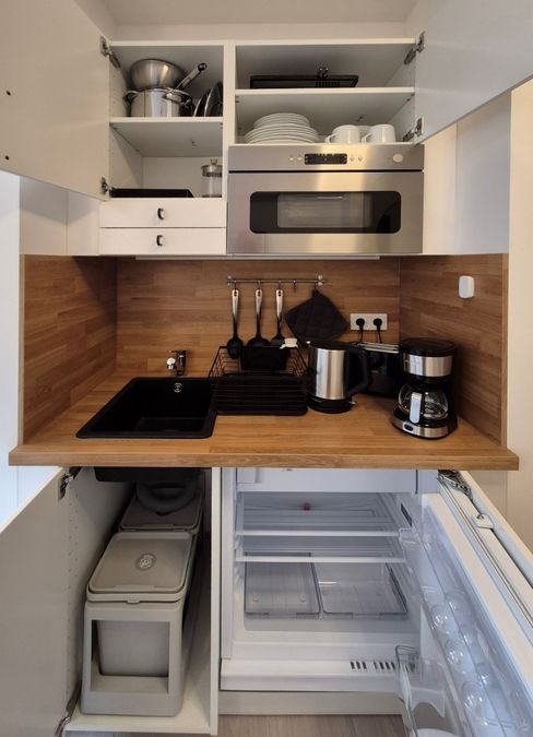 enlarge the image: Well-equipped, compact kitchen with a sink, microwave, and refrigerator, offering a functional and well-organized layout. Photo: Thomas Biermann